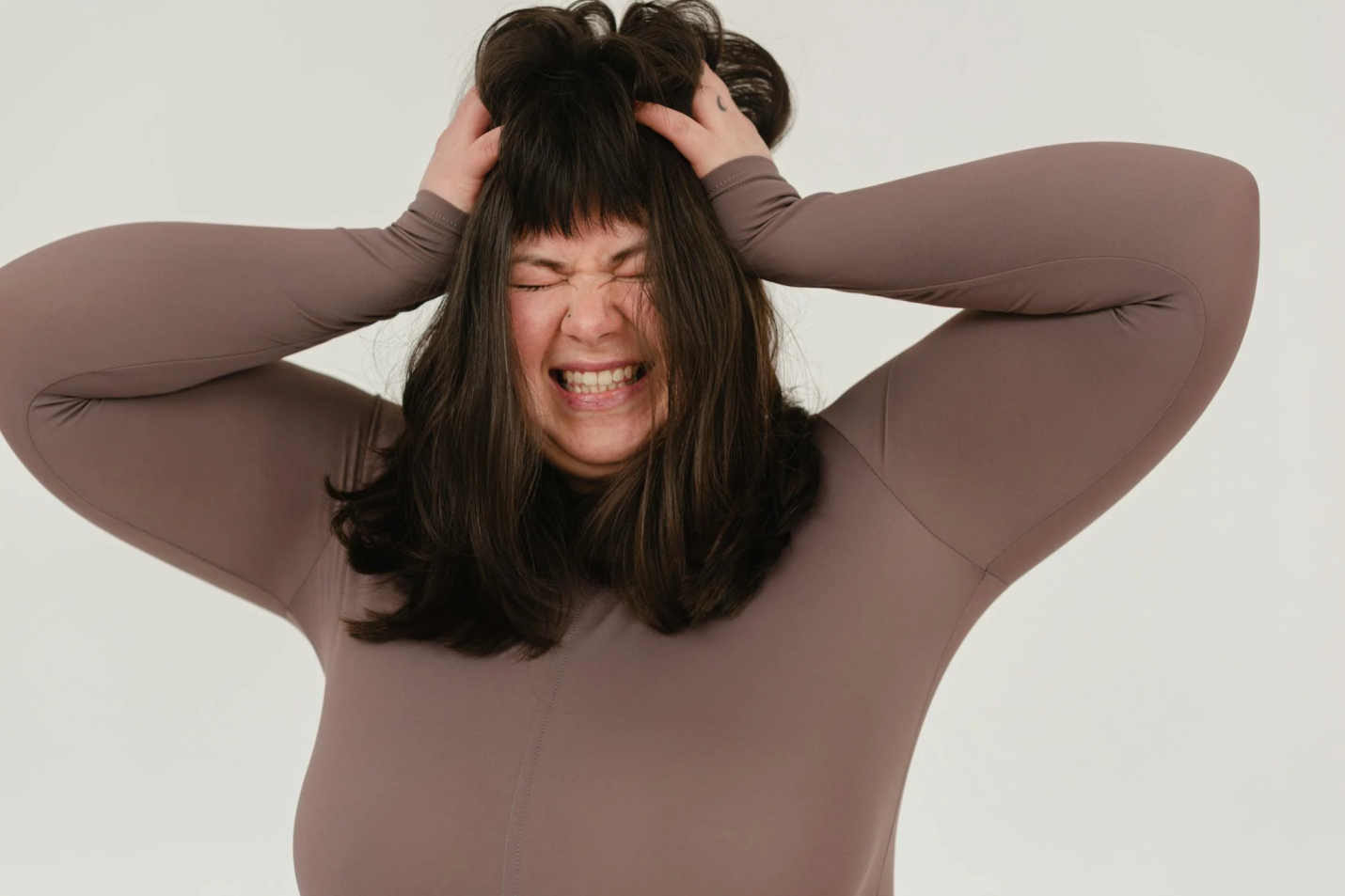 An overweight woman looks upset as she clutches her hair.